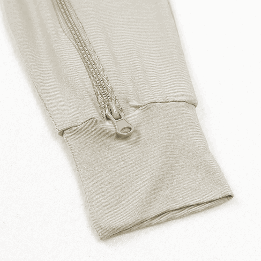 close-up of the cuffed leg opening with a drawstring detail on cream-colored sleeveless bamboo baby overalls
