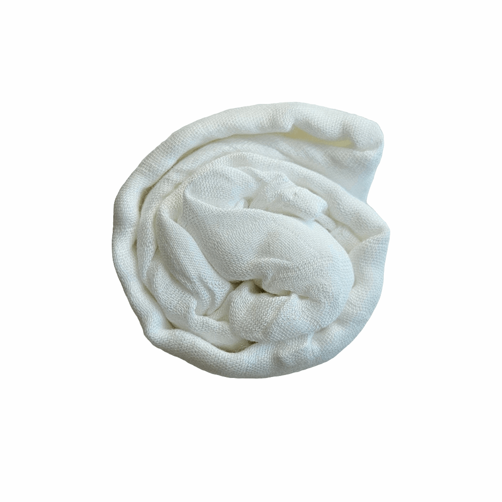A neatly folded white bamboo swaddle blanket, coiled into a compact, circular shape. The blanket appears soft and breathable, showcasing its lightweight and comfortable texture ideal for newborns.