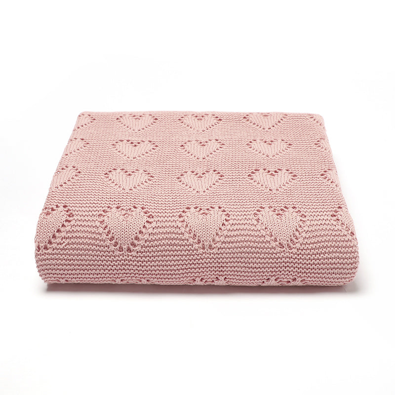 Issy & Lilo organic cotton blanket in blush pink, neatly folded, showcasing a heart-knit design