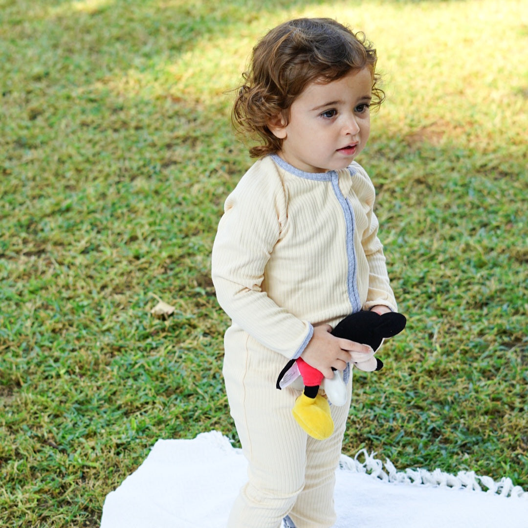 Toddler wearing a smart organic cotton zipper romper in cream while standing on a blanket outdoors.