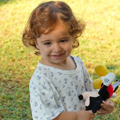 Toddler playing outdoors, holding a soft toy, dressed in an Issy & Lilo light blue organic cotton baby bodysuit